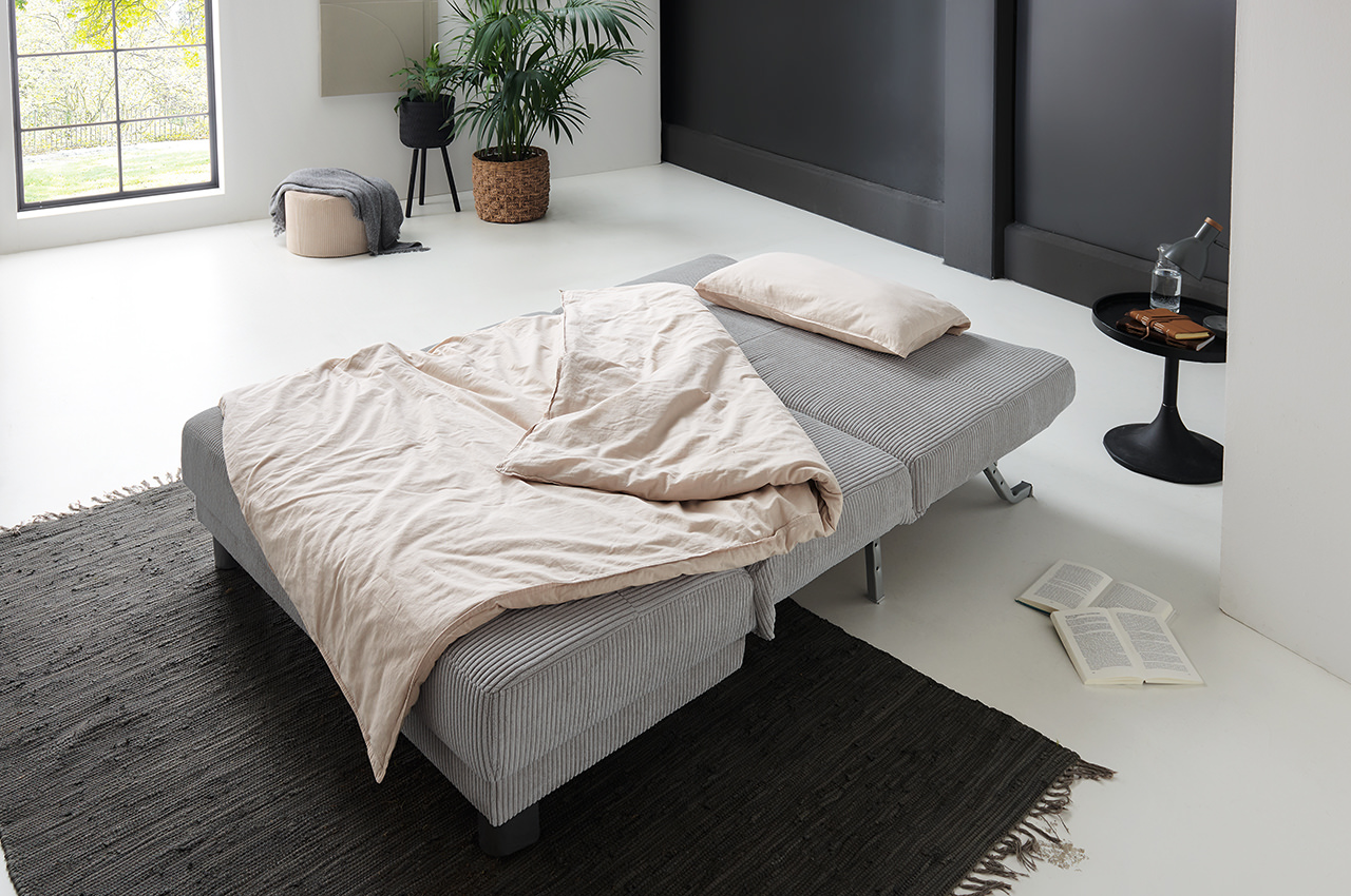 gina faltsofa schlafsofa stoff lincoln 86 grau milieubild aufgeklappte liegeflaeche mit decken